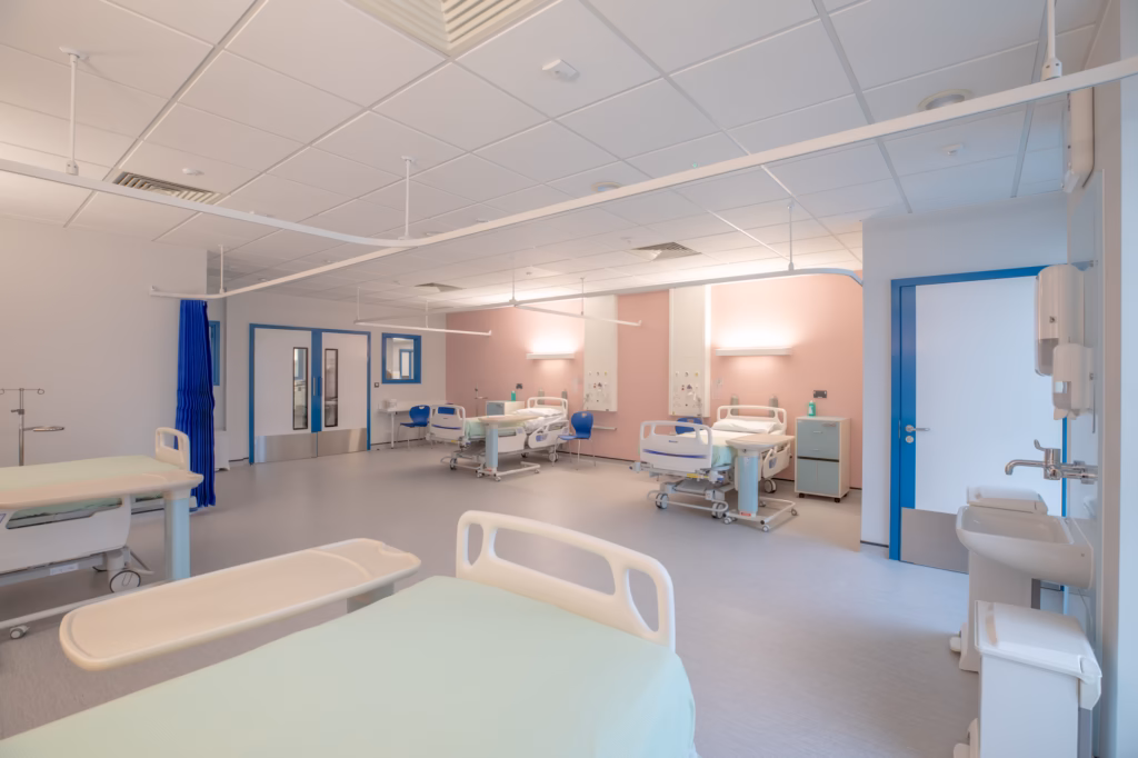Interior of the modular multi‑storey ward at Royal Shrewsbury Hospital showing four‑bed bays and clinical space